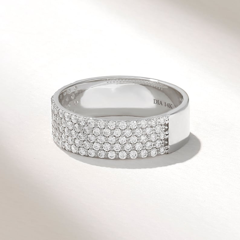 May include: A white gold band ring with five rows of pave set diamonds. The ring is marked "DIA 14K" on the inside.