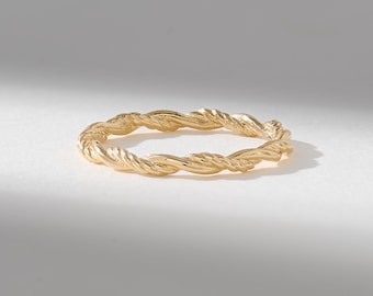 Puede incluir: Un anillo circular fino elaborado en oro amarillo pulido. La banda presenta una textura continua de cuerda trenzada que envuelve toda la circunferencia, creando un patrón de espiral repetitivo con un acabado metálico reflectante.