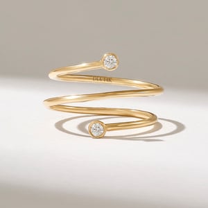 Puede incluir: Un anillo de espiral de oro con dos pequeños diamantes redondos. El anillo está marcado con "DIA 14K".