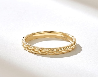 May include: A yellow gold ring featuring a continuous braided or woven texture around the entire band. The interior of the band is clearly engraved with the text DIA 14K, indicating the metal purity and material composition of the jewelry piece.