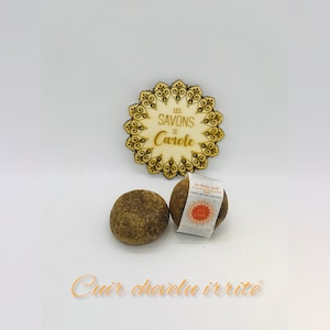 Peut inclure: Deux savons bruns avec une étiquette qui indique "Le Petit Savon" et "Savons de Carole". Les savons sont sur un fond blanc.