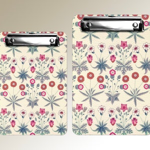 Può includere: Due clipboard con un motivo floreale. I clipboard sono bianchi con uno sfondo marrone chiaro e presentano un motivo ripetitivo di fiori blu, rosa e rossi.