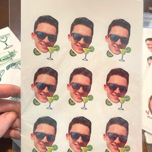 May include: Nine white stickers with a man's face wearing sunglasses and a margarita glass. Each sticker has a lime wedge next to the glass.