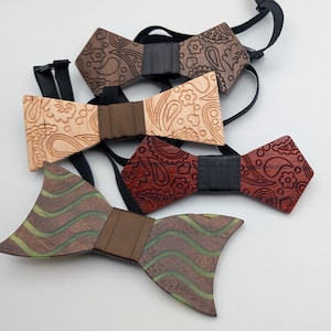 Può includere: Quattro papillon in legno con diversi motivi. I papillon sono marroni, beige, rossi e verdi con un motivo a righe marroni, nere e verdi.