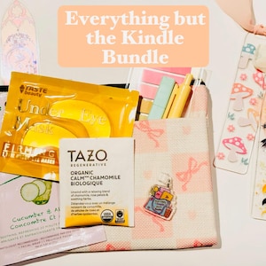 May include: A bundle of self-care items and accessories, including eye masks, tea, and bookmarks. The image includes a small tote bag, pens, and a bookmark with the text "2026". The text "Everything but the Kindle Bundle" is also visible.