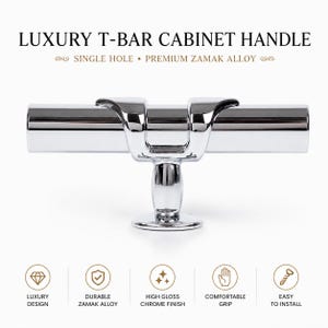 Pode incluir: Um puxador de móvel em forma de T feito de liga de zamak com acabamento cromado brilhante. Apresenta uma base de montagem de furo único e uma barra cilíndrica horizontal com um suporte central. Texto: LUXURY T-BAR CABINET HANDLE, SINGLE HOLE.
