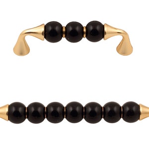 Peut inclure: Deux poignées de tiroir dorées avec des perles en céramique noires. La poignée du haut a trois perles et la poignée du bas en a cinq.
