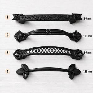 Könnte beinhalten: Vier schwarze Metall-Schrankgriffe, nummeriert von 1 bis 4. Griff 1 hat ein Blumenmuster und ist 96 mm groß. Griff 2 ist geschwungen und 128 mm groß. Griff 3 hat ein Gitterdesign und ist 96 mm groß. Griff 4 hat blattförmige Enden und ist 128 mm groß.