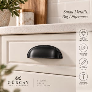 May include: A matte black cup pull drawer handle mounted on a cream-colored cabinet door. The image includes the text "Small Details. Big Difference." and icons indicating premium zinc alloy, multiple finishes, multiple sizes, and screws included.