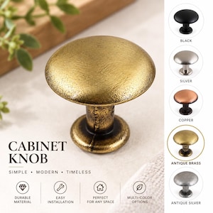 Op de afbeelding: Een ronde kastknop met een getextureerde antiek messing afwerking. De afbeelding toont de knop in het midden met een verticale kolom aan de rechterkant die vijf kleurvariaties weergeeft: zwart, zilver, koper, antiek messing en antiek zilver.