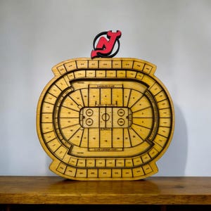 May include: A wooden model of the Prudential Center, home of the New Jersey Devils NHL team. The model is a detailed replica of the arena's seating chart, with the Devils' logo on top.