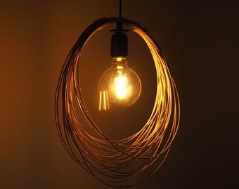 Könnte beinhalten: Eine Pendelleuchte aus geflochtenem Draht mit einer warm leuchtenden Glühbirne im Inneren.