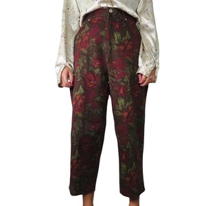 Könnte beinhalten: Hoch taillierte Hose mit Blumenmuster in Rot-, Grün- und Brauntönen. Die Hose hat eine weite Beinweite und eine verkürzte Länge.