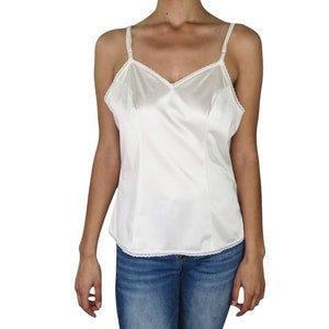 Könnte beinhalten: Ein weißes Satin-Top mit Spitzenbesatz. Das Top hat dünne, verstellbare Träger und einen V-Ausschnitt.