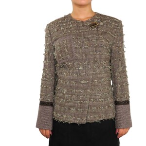 May include: A brown tweed jacket with a frayed texture and a small pocket on the left side. The jacket has a brown button closure and brown trim on the sleeves.