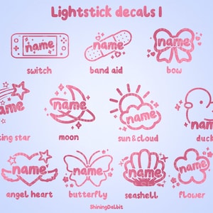 May include: Pink and white lightstick decals with various designs, including a shooting star, moon, sun and cloud, duck, angel heart, butterfly, seashell, and flower. Each design features the word "name" in a stylised font.