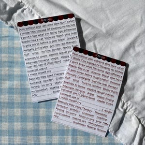 Könnte beinhalten: Zwei rechteckige weiße Karten mit einem dunkelroten und schwarzen gewellten Rand und der Aufschrift AO3 tags. Die Karten enthalten eine Liste gedruckter Begriffe wie Porn without plot, extreme slow burn, canon, I Wrote This Instead Of Sleeping, no bitches, I don't know what I'm doing, Age difference, Reader has a cat, Violence, Blood, slow burn, It gets worse before it gets better, Oneshot, Mentally (un)stable, just like real therapy!, fluff, smut, hurt/no comfort, Bodily fluids, enemies to lovers, explicit sexual content, Alternate Universe, Angst, Happy Ending, incorrect use of [food item], reader insert, I made myself cry, Basically they need Therapy, x reader, Romance, Comfort, Crossover, Friendship, Flirting, Im sorry, Idiots in love, Love Hate, hurt/comfort, making out, Manipulation, POV und Soulmates Teasing Tension.