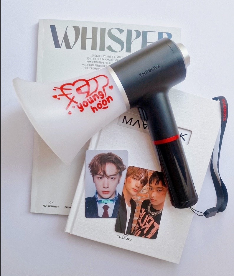 以下が含まれることがあります： 赤い文字で「#younghoon」と書かれた白いメガホンと、黒と銀のヘアドライヤーに「THEBOYZ」と書かれている。THEBOYZグループのK-POPアイドルのフォトカードが3枚ある。