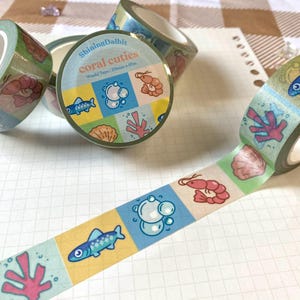 Könnte beinhalten: Eine Rolle Washi-Tape mit einem Korallenriff-Motiv. Das Band zeigt verschiedene Meerestiere, darunter Fische, Garnelen und Korallen. Das Band ist 20 mm breit und 10 m lang. Der Text auf dem Band lautet "ShiningDalbit coral cuties Washi Tape: 20mm x 10m".
