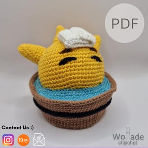 May include: A handmade crochet figure of a yellow character wearing a white chef's hat, sitting in a brown and blue bowl. The figure has black eyes and is made of yarn. The image includes the text "PDF".