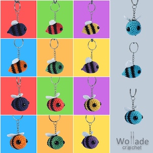 Op de afbeelding: Een set van 12 gehaakte bijen sleutelhangers in verschillende kleuren, waaronder zwart, geel, groen, rood, blauw en paars. Elke sleutelhanger heeft een bij met zwart-witte strepen en een klein, rond gezicht met zwarte ogen. De sleutelhangers worden getoond op een kleurrijke achtergrond.