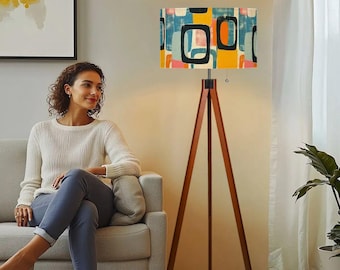 May include: A wooden tripod floor lamp with a colorful geometric patterned lampshade. The lampshade has a mix of blue, yellow, orange, and pink colors.