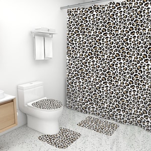 May include: A bathroom set with a leopard print shower curtain, toilet seat cover, and two bath mats. The shower curtain and bath mats are white with brown leopard spots.