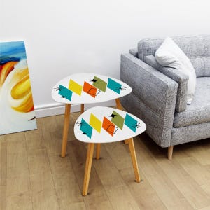 May include: A set of two nesting tables with a white top and wooden legs. The tabletops feature a geometric pattern in shades of yellow, orange, green, and blue.