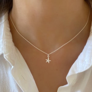 May include: A silver chain necklace with a small, silver starfish pendant.