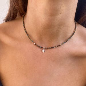 May include: A silver necklace with a small starfish charm. The necklace is made of tiny, multi-colored beads.