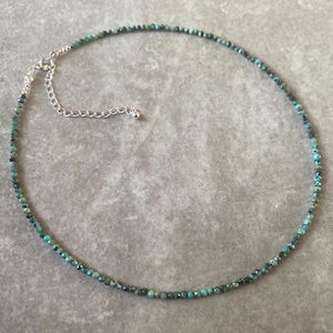 May include: A delicate turquoise gemstone necklace with a silver clasp. The necklace is made of small, round beads and is perfect for layering.