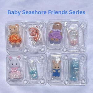 May include: Baby Seashore Friends Series set featuring four flocked animal figures in clear plastic packaging. Includes a bear in orange, a brown bear in purple, a white rabbit in pink, and a tan rabbit in blue, with various small accessories.
