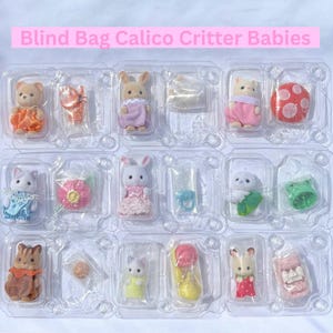May include: A collection of twelve Calico Critter baby figures in individual clear plastic blister packs. Each pack contains a small flocked animal figure wearing colorful clothing and a tiny accessory, arranged in a grid with the text Blind Bag Calico Critter Babies.