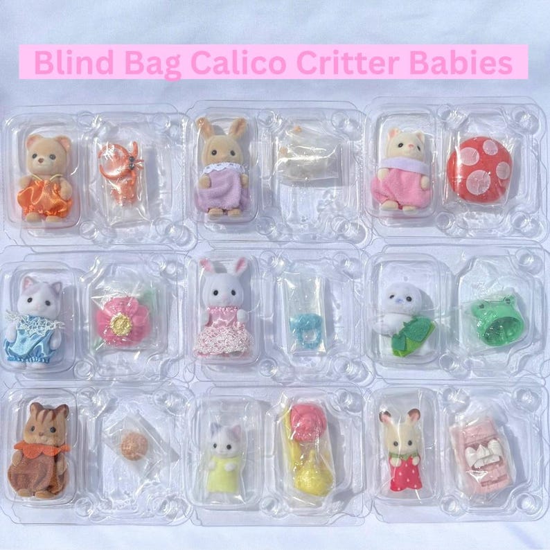 May include: A collection of twelve Calico Critter baby figures in individual clear plastic blister packs. Each pack contains a small flocked animal figure wearing colorful clothing and a tiny accessory, arranged in a grid with the text Blind Bag Calico Critter Babies.