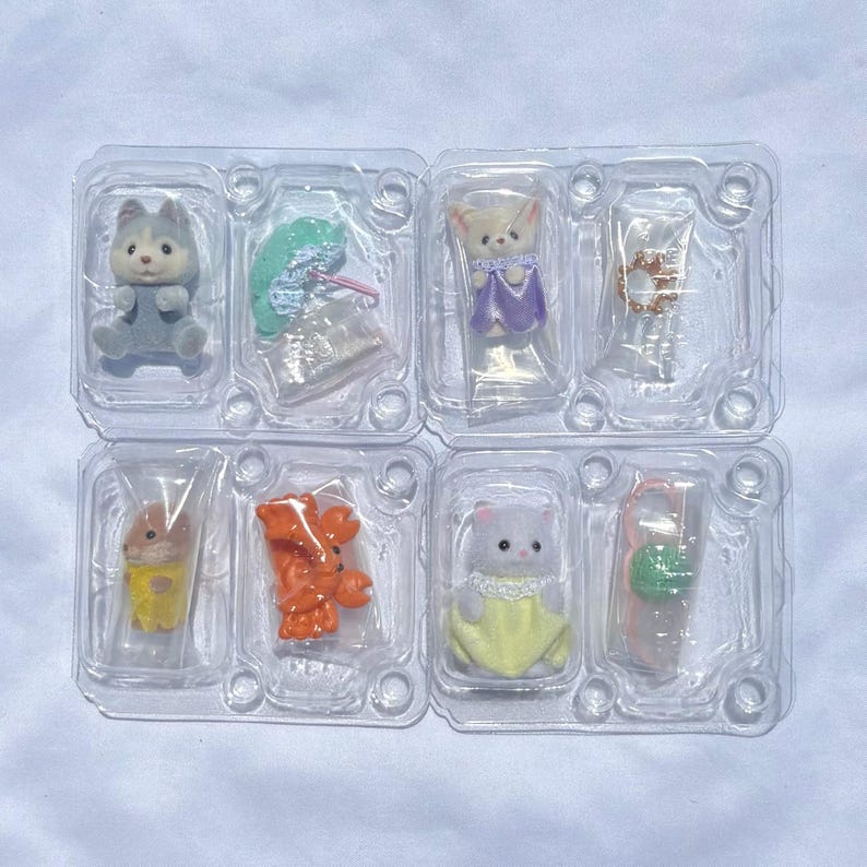 May include: A set of four clear plastic blister packs containing miniature flocked animal figurines and small accessories. The figures include a grey husky, a cream-colored cat in a purple dress, a brown hamster, and a white cat in a yellow dress.