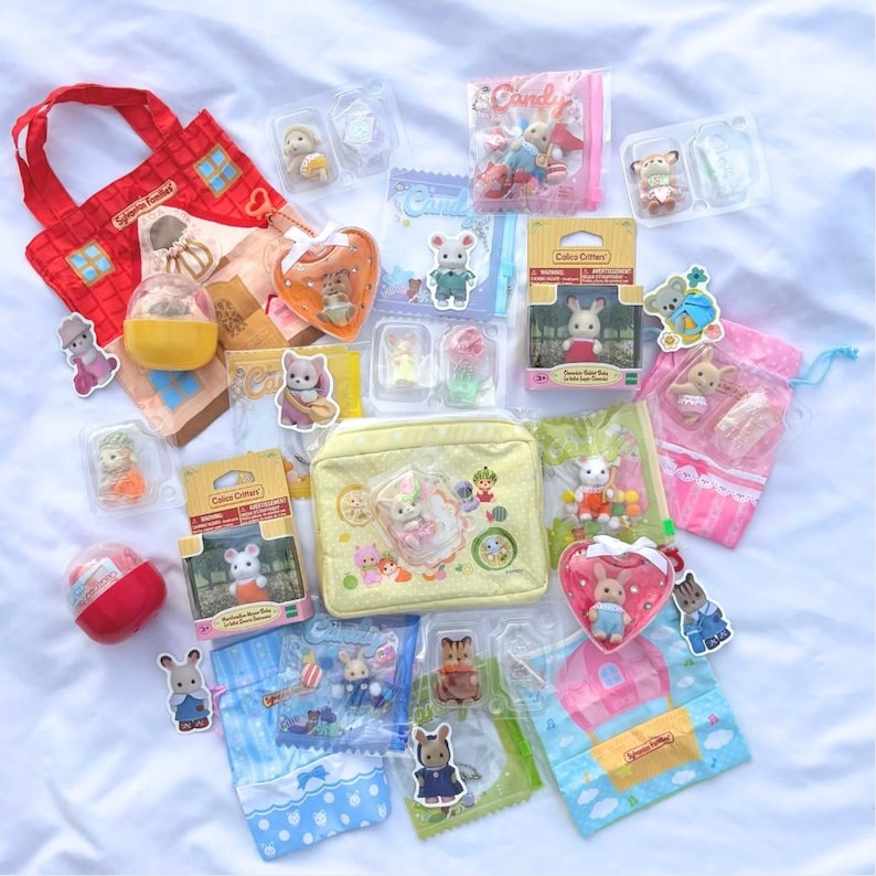 May include: A collection of Calico Critters toys and accessories, including miniature animal figures, packaged in boxes, bags, and clear plastic containers. The items are arranged on a white surface, with a red tote bag and a yellow cosmetic bag.