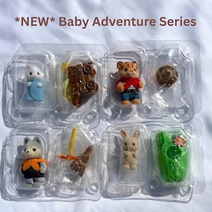 May include: Four small flocked animal figures in clear plastic packaging labeled *NEW* Baby Adventure Series. The set includes a white cat in a blue blanket, a tiger in a red shirt, a gray wolf in an orange vest, and a tan rabbit, with accessories.