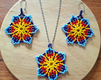 Puede incluir: Un conjunto de collar y pendientes de cuentas con un diseño de estrella. El collar y los pendientes están hechos con cuentas azules, amarillas, naranjas y rojas.