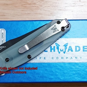 May include: A blue box with a white label that says "HMFADE KNIFE COMPANY" and a butterfly logo. A gray and black pocket knife with a silver pocket clip is on top of the box. The text "Knife shown not included @Austin Outdoors" is written on the box.