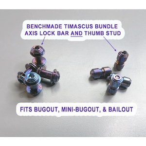 Op de afbeelding: Een Benchmade Timascus-bundel met axis-lock-stangen en duimknoppen met een metallic, iriserende blauwe en paarse afwerking. De tekst luidt: BENCHMADE TIMASCUS BUNDLE AXIS LOCK BAR AND THUMB STUD en FITS BUGOUT, MINI-BUGOUT, & BAILOUT.