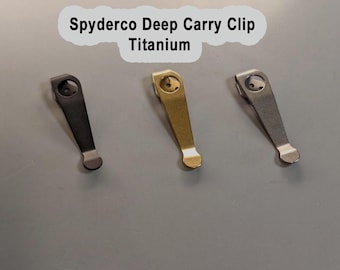 May include: Three Spyderco deep carry titanium clips in black, gold, and silver finishes. Each clip features a rounded top with a circular mounting hole and a flared bottom end. The text Spyderco Deep Carry Clip Titanium is visible.