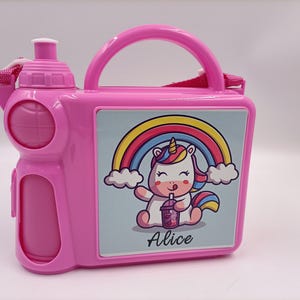 Può includere: Borraccia rosa con manico e tracolla. La borraccia presenta un design a unicorno dei cartoni animati con un arcobaleno e il nome "Alice". Ha un vano integrato per uno spuntino o un piccolo oggetto.