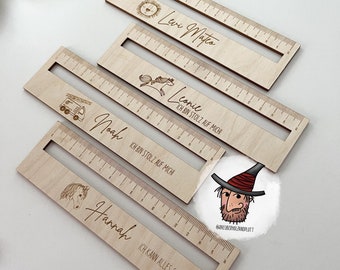 May include: Four wooden rulers with different designs and names. The rulers are made of light wood and have a white background. The names on the rulers are Levi Mateo, Leonie, Noah, and Hannah. Each ruler has a different design, including a sun, a horse, a fire truck, and a unicorn. The rulers are all 30 cm long.