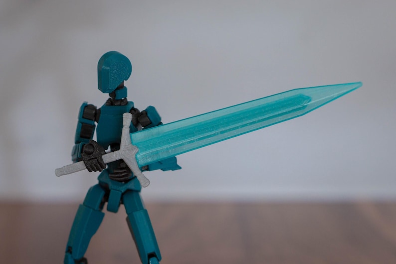 Puede incluir: Una figura de acci&oacute;n azul turquesa sosteniendo una espada azul transl&uacute;cida con una empu&ntilde;adura plateada.