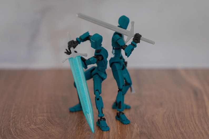 Puede incluir: Dos figuras de acci&oacute;n articuladas de color azul turquesa sosteniendo espadas. Una figura sostiene una espada plateada, la otra sostiene una espada azul turquesa.