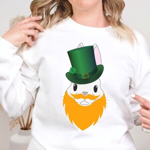 May include: White sweatshirt with a graphic of a white bunny wearing a green leprechaun hat with a gold buckle and an orange beard.