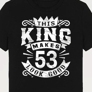 Op de afbeelding: Zwart T-shirt met een wit grafisch ontwerp met de tekst "This King Makes 53 Look Good" met een kroon en sierlijke krulwerk.