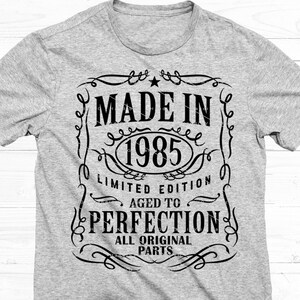 May include: A gray t-shirt with a black graphic design that says "Made in 1985 Limited Edition Aged to Perfection All Original Parts".