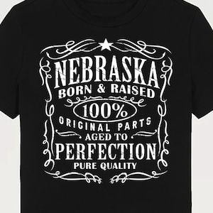 May include: Black t-shirt with a white graphic design that says "Nebraska Born & Raised 100% Original Parts Aged to Perfection Pure Quality".