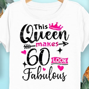 May include: A white t-shirt with black text that reads "This Queen makes 60 look fabulous". The text is decorated with a pink crown, a pink arrow, and pink hearts.